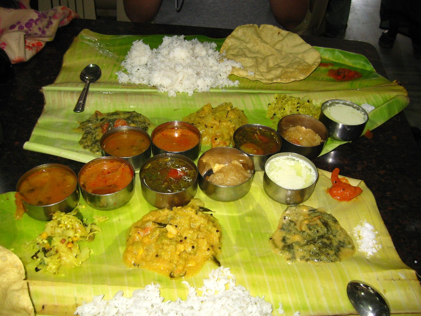 A full South Indian vegetarian meal served on a banana leaf with rice, papad and small bowls of curry