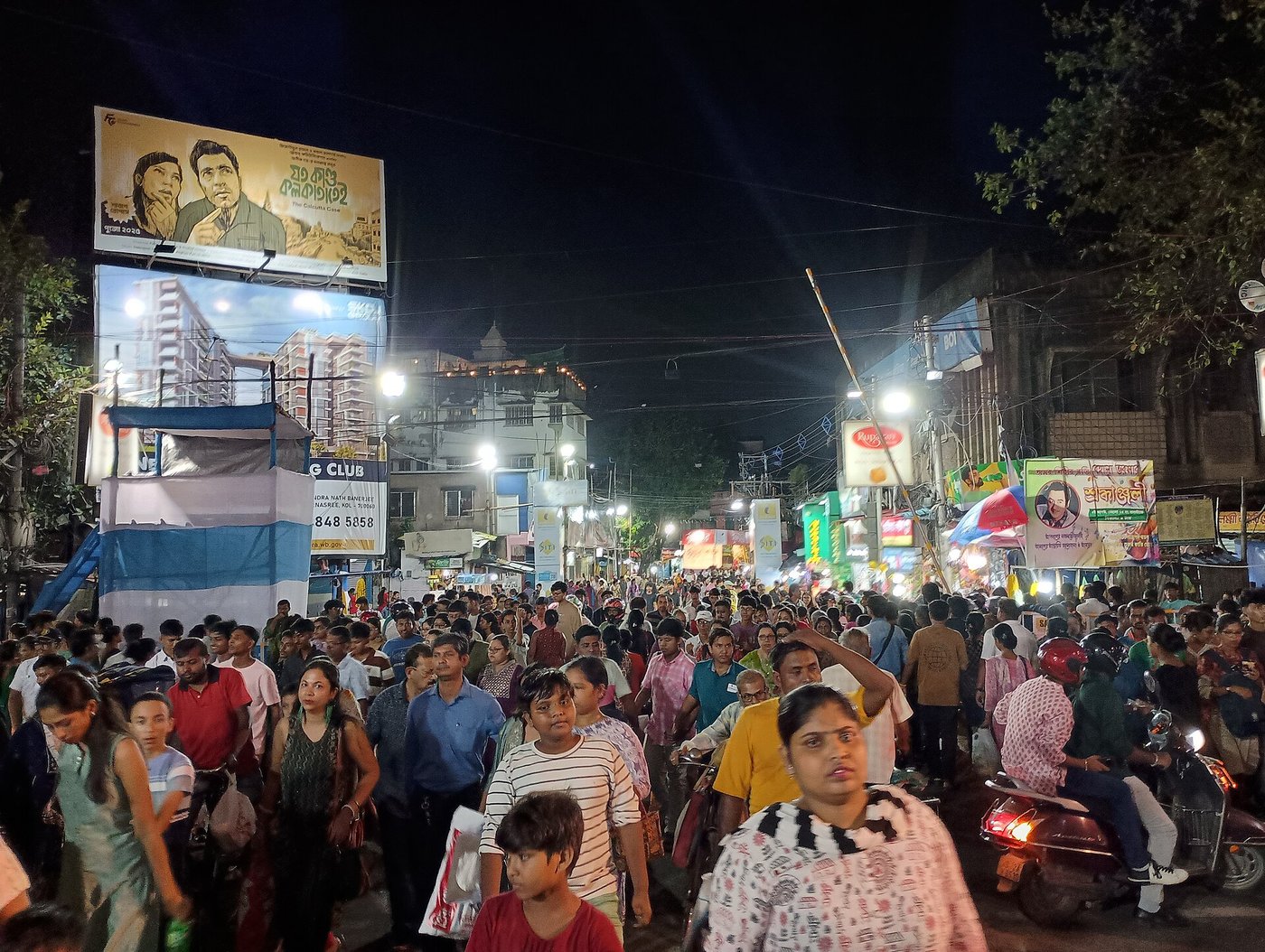 A huge night time crowd on a lit up street in Behala, Kolkata during Durga Puja