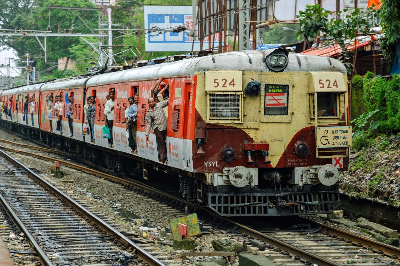 A Mumbai local train with passengers leaning out of the open doors